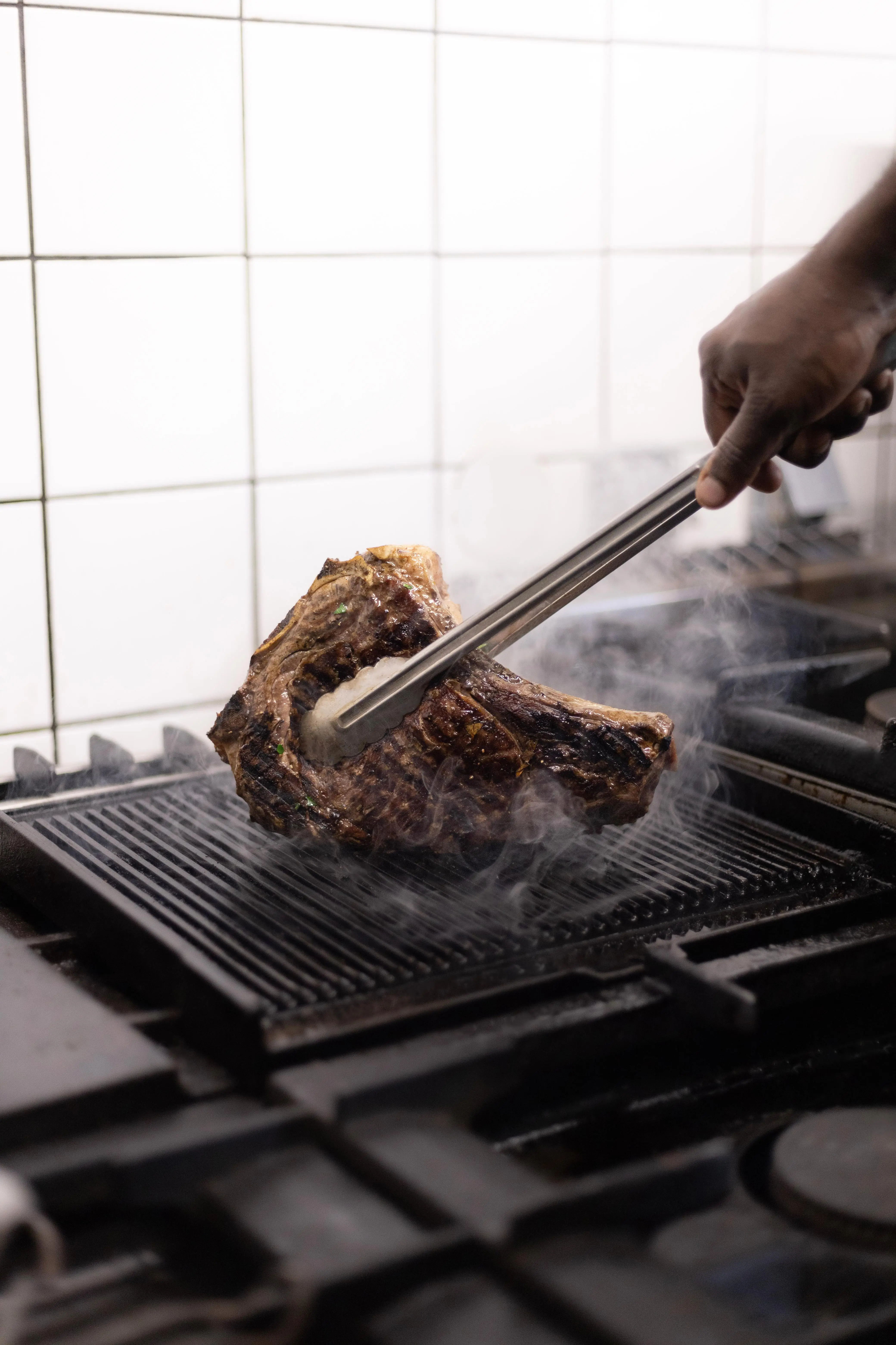 Le chef grille une pièce de viande à la pince